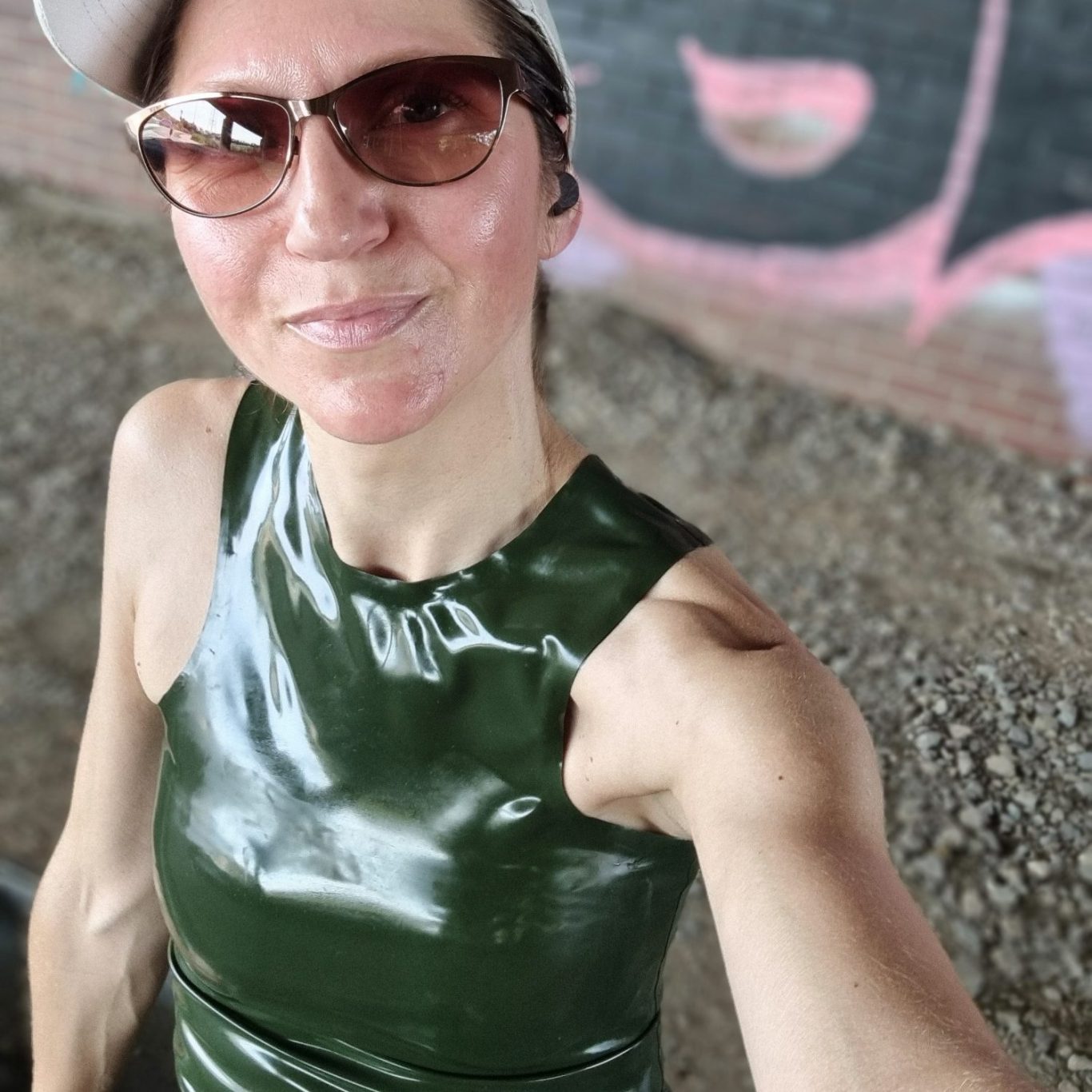 Latextanktop in olive, sportlich kombiniert mit Sonnenbrille und Cap.