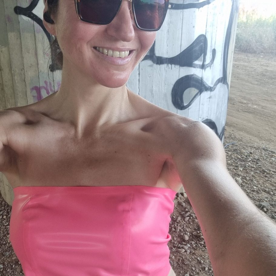 Latexbandeautop in pink, sportlich kombiniert mit Sonnenbrille und Cap.